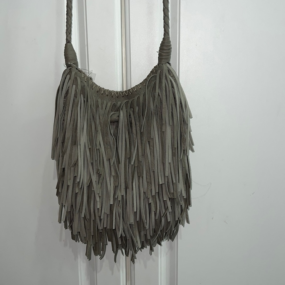 Gray fringe crossbody bag. Button closure with toggle. Inside zippered pocket.
